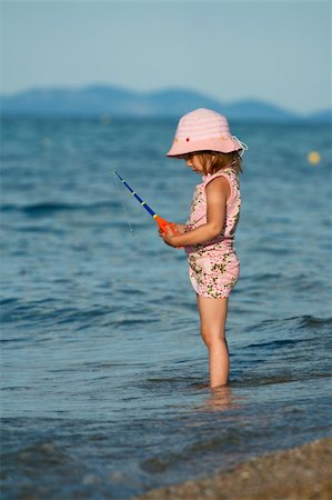 Little pretty girl trying to catch fish in the blue sea. Playing at sunset. Stock Photo - Budget Royalty-Free & Subscription, Code: 400-04666810