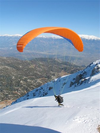 deltaplano - Paraglider with an bright orange wing forward launching off a snow capped mountain. Babadag, Oludeniz, southern Turkey. Fotografie stock - Microstock e Abbonamento, Codice: 400-04667027