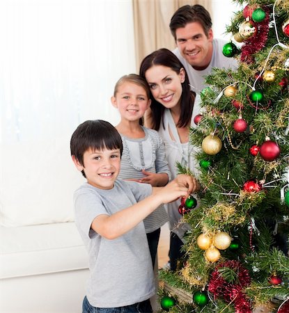 Smiling family decorating a Christmas tree in the living-room Foto de stock - Super Valor sin royalties y Suscripción, Código: 400-04660699