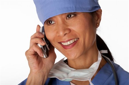 Closeup, cropped view of an Asian female medical professional wearing scrubs and talking on a cell phone. Horizontal shot. Isolated on white. Stock Photo - Budget Royalty-Free & Subscription, Code: 400-04674104