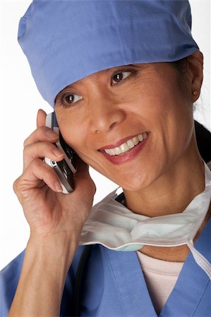 Closeup, cropped view of an Asian female medical professional wearing scrubs and talking on a cell phone. Vertical shot. Isolated on white. Stock Photo - Budget Royalty-Free & Subscription, Code: 400-04674105