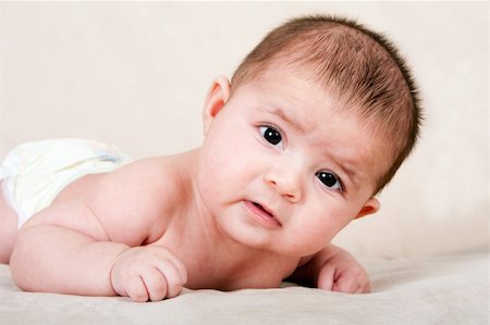 Cute Caucasian Hispanic baby infant laying on belly lifting head making funny expression. Stock Photo - Budget Royalty-Free & Subscription, Code: 400-04675210