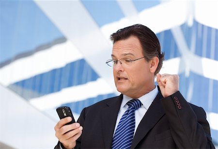 simsearch:400-04608943,k - Excited Businessman Looking at Cell Phone Clinches His Fist in Joy Outside of Corporate Building. Stock Photo - Budget Royalty-Free & Subscription, Code: 400-04677907