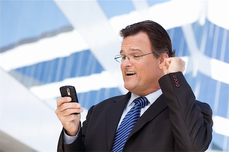 simsearch:400-04608943,k - Excited Businessman Looking at Cell Phone Clinches His Fist in Joy Outside of Corporate Building. Stock Photo - Budget Royalty-Free & Subscription, Code: 400-04678367