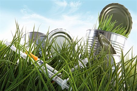 simsearch:400-07053928,k - Syringe needles and food cans left in the grass with blue sky Photographie de stock - Aubaine LD & Abonnement, Code: 400-04678647