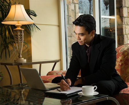 simsearch:400-05209351,k - A young Asian businessman looking at a laptop computer whiles taking notes on a notebook. Horizontal shot. Stock Photo - Budget Royalty-Free & Subscription, Code: 400-04671883