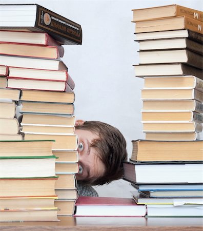 simsearch:400-04622920,k - Young surprised student hide behind stacked books Fotografie stock - Microstock e Abbonamento, Codice: 400-04672137