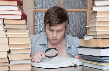 Young crazy student with loupe  between books searching something Photographie de stock - Aubaine LD & Abonnement, Code: 400-04672140