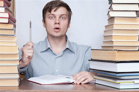 simsearch:400-04622920,k - Young crazy discontent student hold pen in one's hand between books Fotografie stock - Microstock e Abbonamento, Codice: 400-04672161