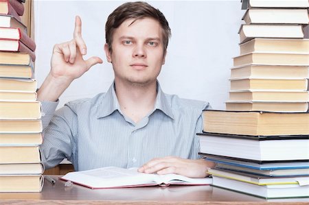 Young serious man show finger to up between books Photographie de stock - Aubaine LD & Abonnement, Code: 400-04672233