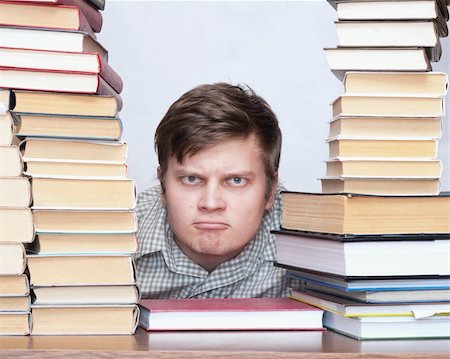 Young serious student with funny face sitting between books Photographie de stock - Aubaine LD & Abonnement, Code: 400-04672249