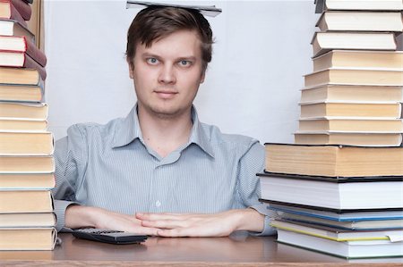 simsearch:400-04622920,k - Young student sitting with book on the head between books Fotografie stock - Microstock e Abbonamento, Codice: 400-04672241