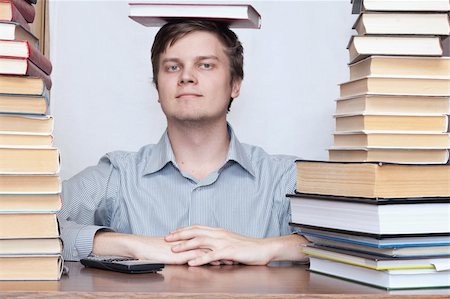 simsearch:400-04622920,k - Young student sitting with book on the head between books Fotografie stock - Microstock e Abbonamento, Codice: 400-04672242