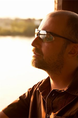 Young man in sunglasses sitting on the bench at sunset Stock Photo - Budget Royalty-Free & Subscription, Code: 400-04672819