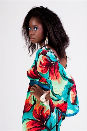 simsearch:400-04672924,k - Attractive young woman wearing a colorful print dress. She is standing with one hand on her hip and looking back towards the camera. Vertical shot. Photographie de stock - Aubaine LD & Abonnement, Code: 400-04672894