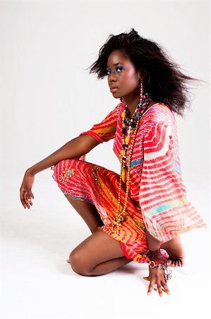 simsearch:649-03883202,k - Attractive young woman wearing a colorful red dress squatting with her arm on her knee. Vertical shot. Photographie de stock - Aubaine LD & Abonnement, Code: 400-04672890