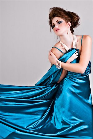 simsearch:400-04672924,k - Attractive young woman standing in a blue satin dress that is being pulled to the side. Vertical shot. Foto de stock - Royalty-Free Super Valor e Assinatura, Número: 400-04672904