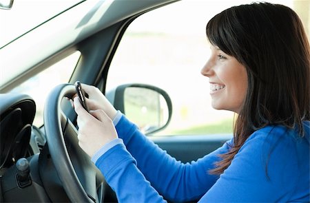 Smiling brunette teen girl using a mobile phone while driving Stock Photo - Budget Royalty-Free & Subscription, Code: 400-04686872