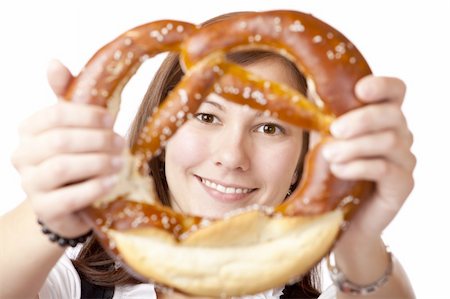 photo of people eating pretzels - Portrait of young woman in Dirndl cloth looking trough Oktoberfest Pretzel. Isolated on white background. Stock Photo - Budget Royalty-Free & Subscription, Code: 400-04689838