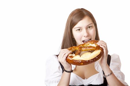 photo of people eating pretzels - Young attractive woman bites in Oktoberfest Pretzel. Isolated on white background. Stock Photo - Budget Royalty-Free & Subscription, Code: 400-04689839