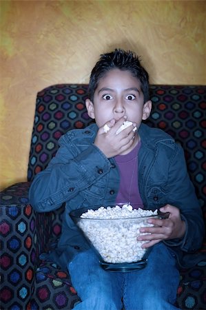 Young Hispanic boy with popcorn watching television Stock Photo - Budget Royalty-Free & Subscription, Code: 400-04682094