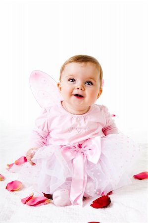 simsearch:400-04436228,k - A cute baby girl dressed in a fairy costume sits amongst flower petals and smiles upwards.  Vertical shot. Stock Photo - Budget Royalty-Free & Subscription, Code: 400-04694254