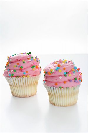 simsearch:400-04178778,k - Two pink gourmet cupcake isolated on white vertical Foto de stock - Super Valor sin royalties y Suscripción, Código: 400-04696780