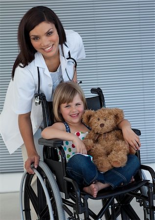 Smiling Little girl on a wheelchair holding her teddy bear Stockbilder - Microstock & Abonnement, Bildnummer: 400-04697266