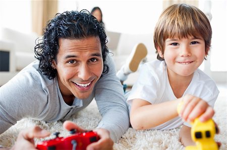 Cheerful father and his son playing video games lying on the floor in the living-room Stock Photo - Budget Royalty-Free & Subscription, Code: 400-04697405