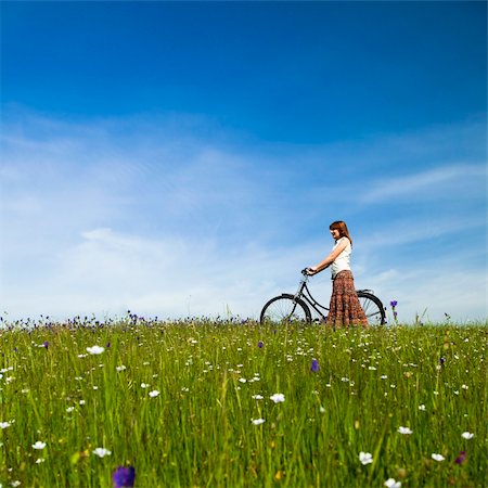 simsearch:400-04201795,k - Happy young woman with a vintage bicycle on a green meadow Fotografie stock - Microstock e Abbonamento, Codice: 400-04697436