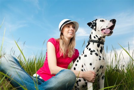 female dalmatian - beautiful young woman in hat sitting in grass with her dalmatian dog pet and smiling. Blue sky in background and green grass in foreground. Stock Photo - Budget Royalty-Free & Subscription, Code: 400-04698755