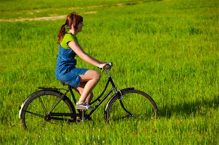 simsearch:400-04201795,k - Happy young woman on a green meadow riding a bicycle Fotografie stock - Microstock e Abbonamento, Codice: 400-04699993