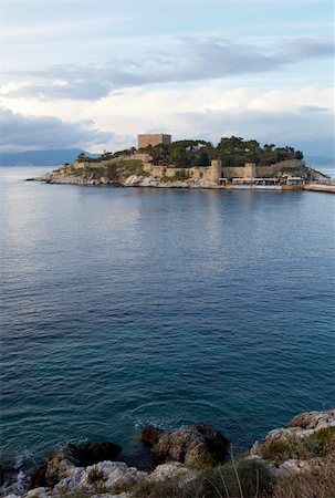 simsearch:400-04473180,k - Pigeon Island Fortress, also known as the Pirates castle, in the Kusadasi harbor, on the Aegean coast of Turkey. Shallow DOF, focus on foreground rocks and water Photographie de stock - Aubaine LD & Abonnement, Code: 400-04690175