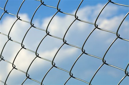 Metal wire fence against blue sky with clouds Stock Photo - Budget Royalty-Free & Subscription, Code: 400-04690513