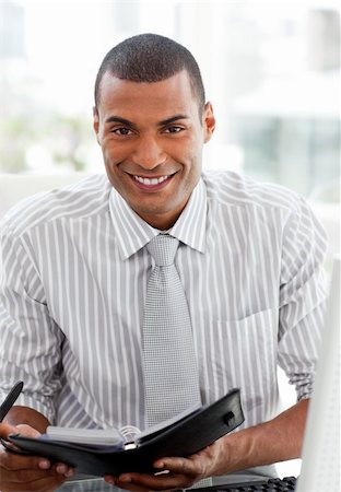 Smiling businessman consulting his agenda in the office Stock Photo - Budget Royalty-Free & Subscription, Code: 400-04690659