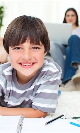 simsearch:6109-07601494,k - Little boy drawing lying on the floor with his parents in the background Stock Photo - Budget Royalty-Free & Subscription, Code: 400-04691676