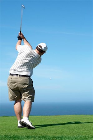 simsearch:400-05038623,k - Young male golfer hitting the ball from the tee box next to the ocean on a beautiful summer day Stock Photo - Budget Royalty-Free & Subscription, Code: 400-04693960