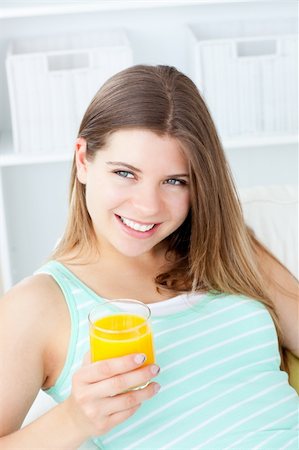 simsearch:400-04708507,k - Charming young woman holding a glass of orange juice sitting on a sofa Stock Photo - Budget Royalty-Free & Subscription, Code: 400-04704934