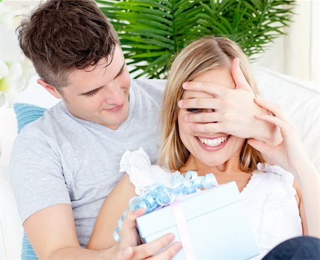 simsearch:400-06415374,k - Young couple looking at the camera with a present in the living-room Stock Photo - Budget Royalty-Free & Subscription, Code: 400-04704948