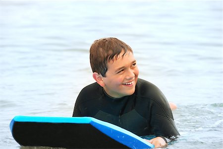 Smiling teenage surfer laying on his bodyboard in the ocean. Stock Photo - Budget Royalty-Free & Subscription, Code: 400-04708948