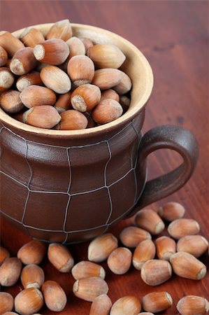 simsearch:400-06520688,k - Ceramic mug with spilled different-sized hazelnuts on a wooden table Stock Photo - Budget Royalty-Free & Subscription, Code: 400-04709486