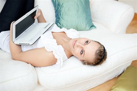 simsearch:400-04709946,k - Attractive young woman surfing the internet lying on a sofa at home Stockbilder - Microstock & Abonnement, Bildnummer: 400-04700424