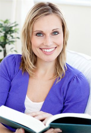 simsearch:6109-06194845,k - Happy woman reading a book sitting on a sofa in the living-room Foto de stock - Super Valor sin royalties y Suscripción, Código: 400-04701472