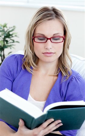 simsearch:400-05716909,k - Young woman with glasses reading a book sitting on a sofa Stock Photo - Budget Royalty-Free & Subscription, Code: 400-04701473