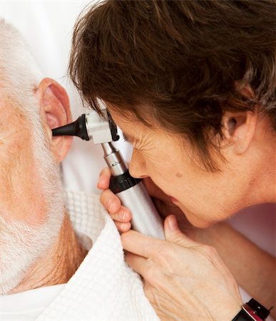 simsearch:400-04419056,k - Closeup of nurse or doctor looking in a patient's ears with an otoscope. Foto de stock - Royalty-Free Super Valor e Assinatura, Número: 400-04701798