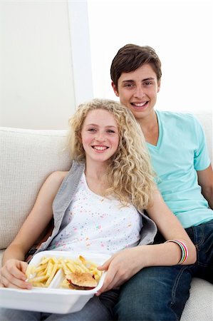 Teen couple eating burgers and fries on the sofa Stock Photo - Budget Royalty-Free & Subscription, Code: 400-04702107