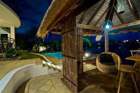 simsearch:400-05317362,k - Luxurious mansion exterior at dusk overlooking pool, canal and Bali hut Foto de stock - Royalty-Free Super Valor e Assinatura, Número: 400-04702825