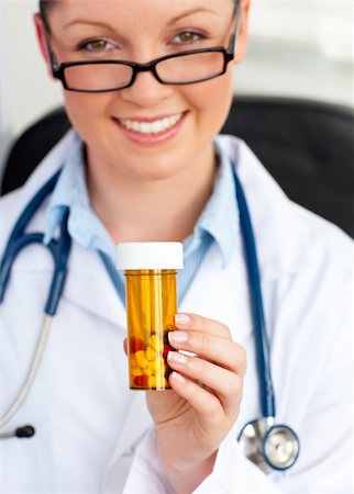 simsearch:400-05748268,k - Glowing young female doctor holding pills sitting in her office Stock Photo - Budget Royalty-Free & Subscription, Code: 400-04714597