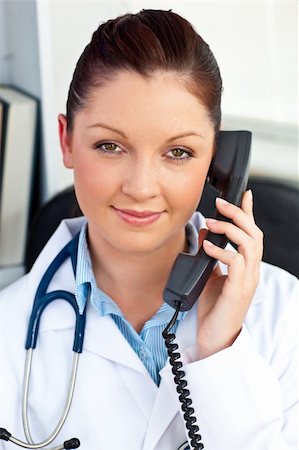 simsearch:400-04704005,k - Portrait of an assertive female doctor phoning in her office sitting at her desk Stock Photo - Budget Royalty-Free & Subscription, Code: 400-04714614