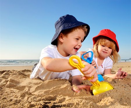 Gorgeous brother and sister ages 4 and 2 have fun digging in the sand at the beach Foto de stock - Super Valor sin royalties y Suscripción, Código: 400-04716246